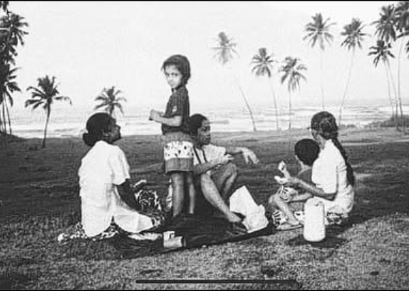 A family sits atop a blanket looking over the seaside in Sri Lanka